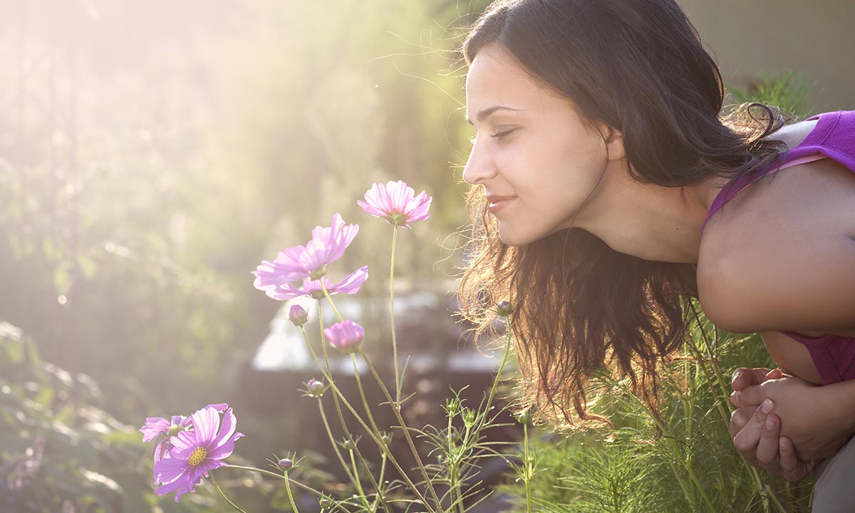 What Comfort Food Are You? Young beautiful woman smells a flower in the garden