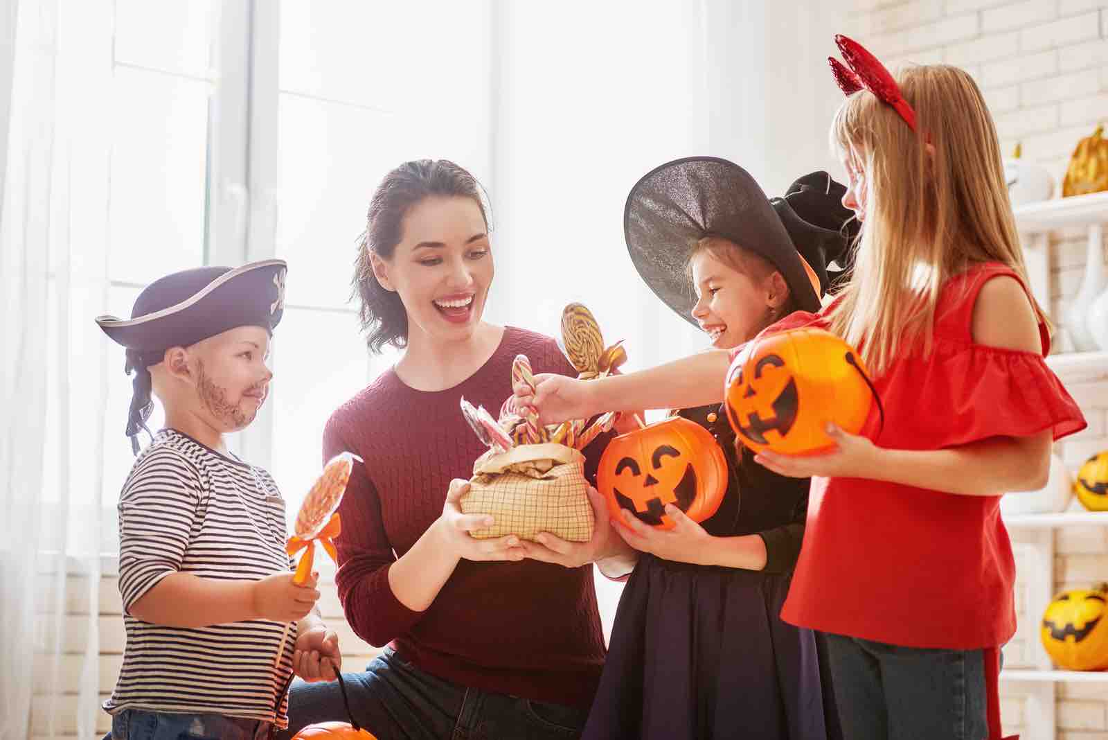 What Fall Food Are You? Happy family celebrating Halloween! Young mom treats children with candy. Funny kids in carnival cos