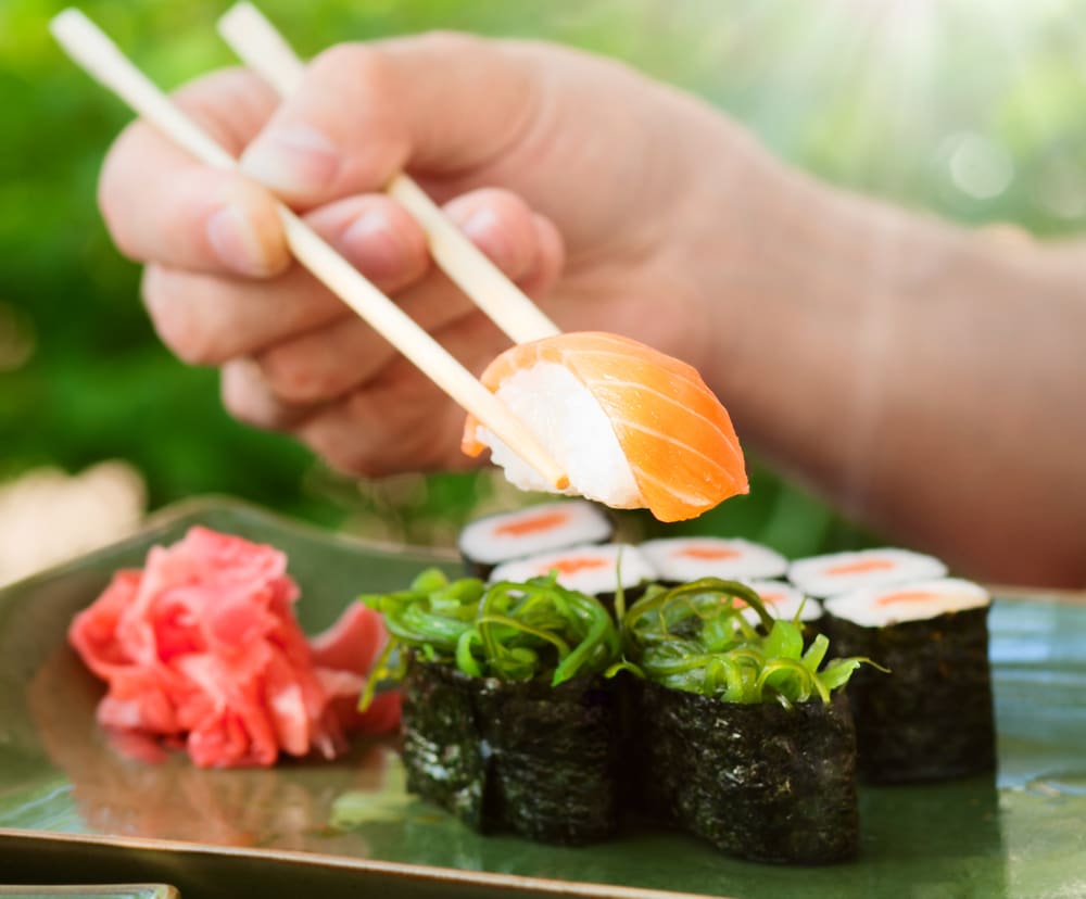 person eating sushi with chopsticks