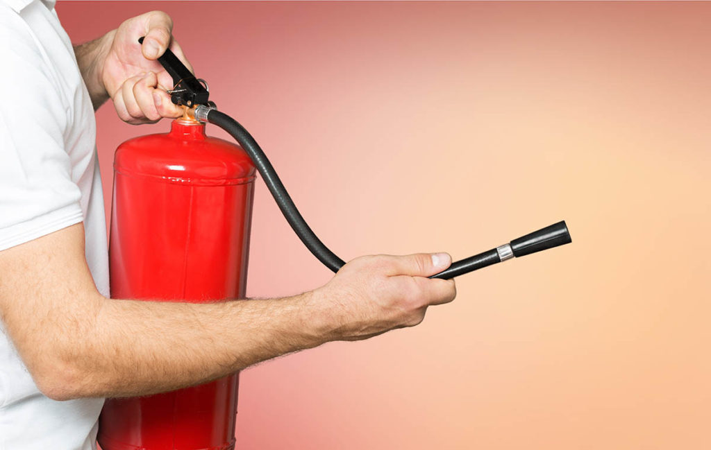 If You Can Pass This Home Safety Quiz, Then Your Home Is Super Safe Man using fire extinguisher against grey background