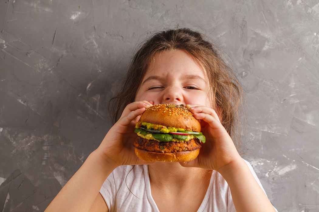 Can We Guess Where You Grew up by Your Taste in Food? Girl Eating A Veggie Burger
