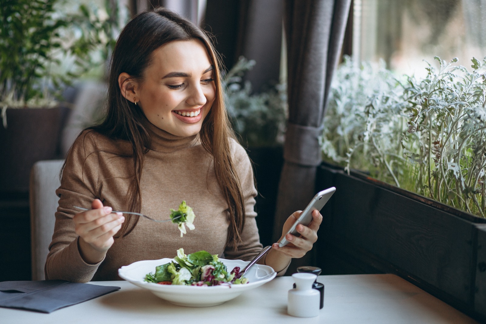 This “Would You Rather” Quiz Will Determine Your True Age Young Woman Eating Salad In A Cafe