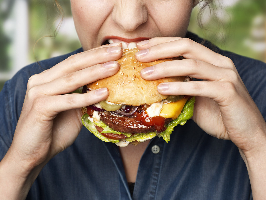 I Bet We Can Guess What Month You Were Born in Based on Your Food Choices Woman Eating Burger
