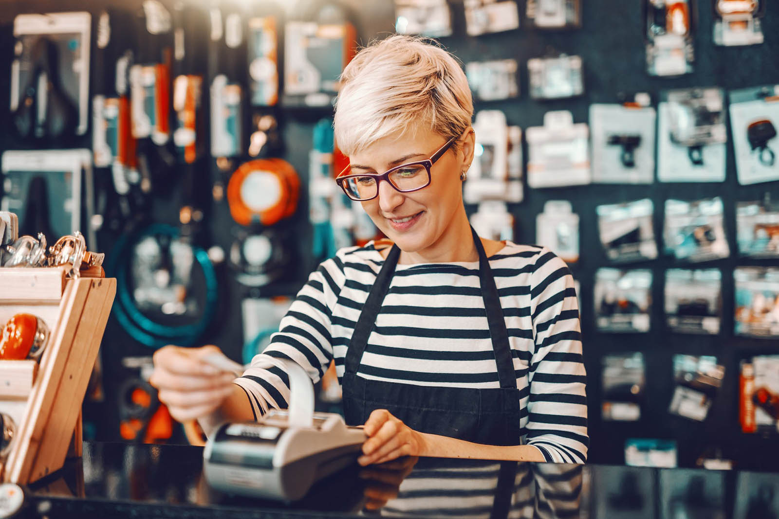Middle School Spelling Quiz Woman In Apron Reaching For Receipt At Store Counter Small Business Owner