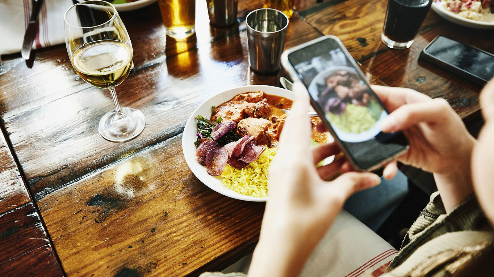 ClutterBug Quiz Woman Taking Photo Of Food With Smartphone While Having Lunch With Friends In Restaurant