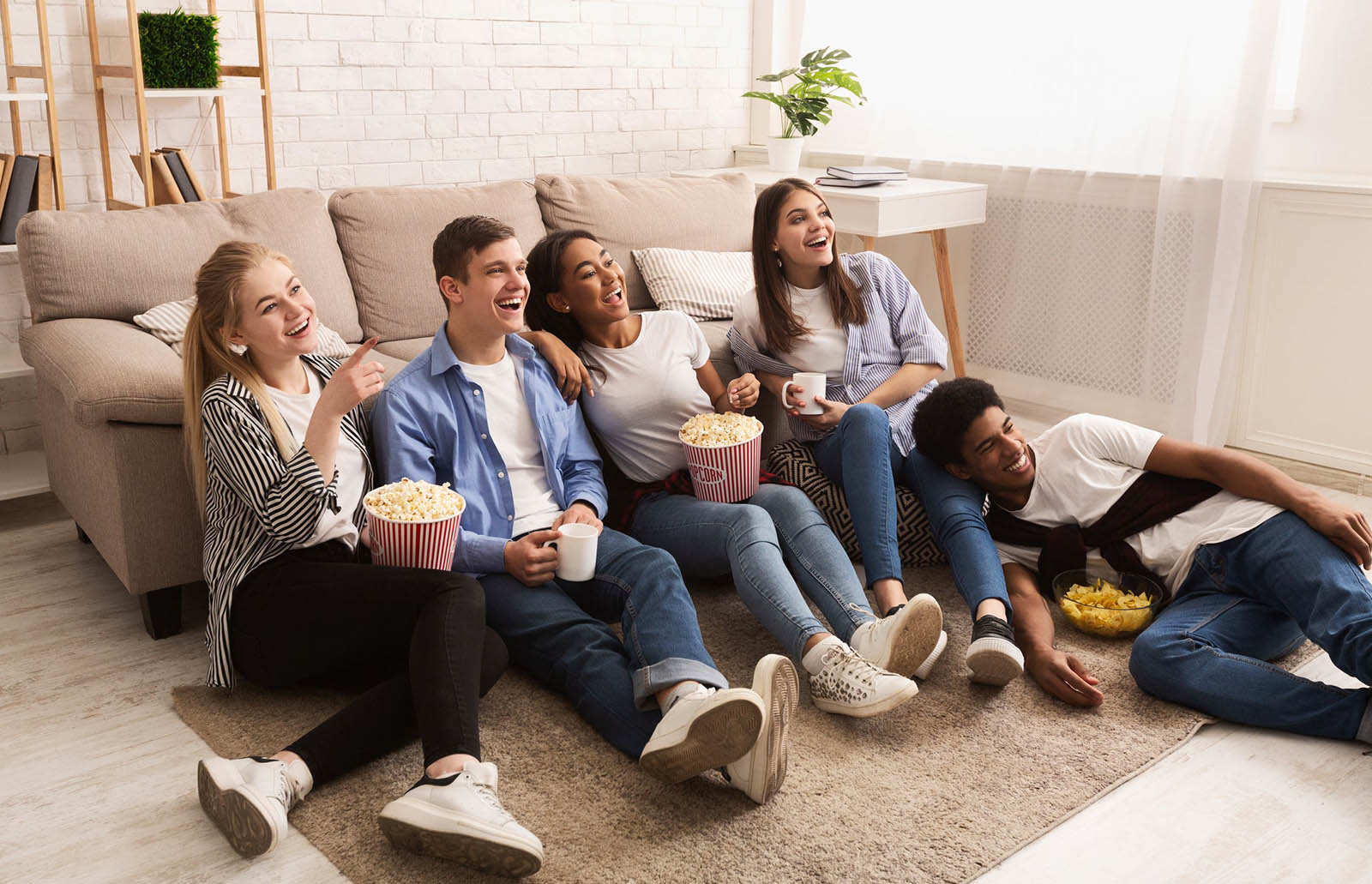 Young Adults Watching Television And Eating Popcorn