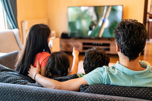 Your Parenting Rules Will Reveal How Nice or Toxic Your Personality Is Parents and their two children watching TV together at home