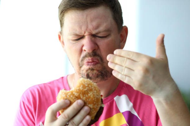 Unhappy man sniffing suspicious burger examining its freshness portrait